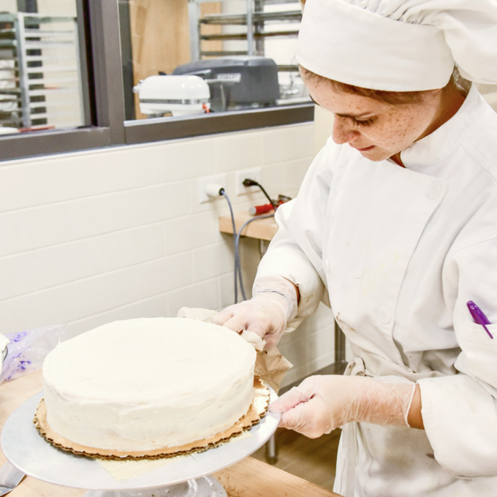 a baker dilligently frosting a white cake