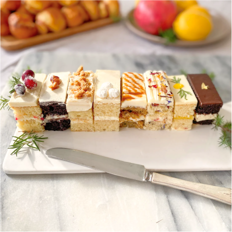 eight rectangular cake slices sitting on a platter with a butter knife