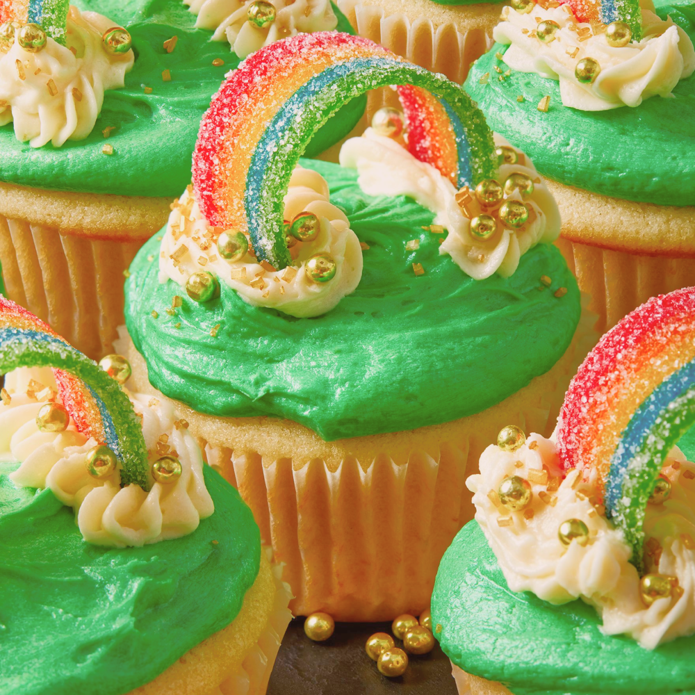 a close-up of a st-patrick's day themed cupcake with green frosting, an airhead xtreme candy strip, and circular golden decorations